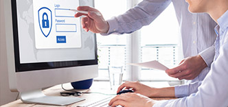 Two people in front of computer with login on screen